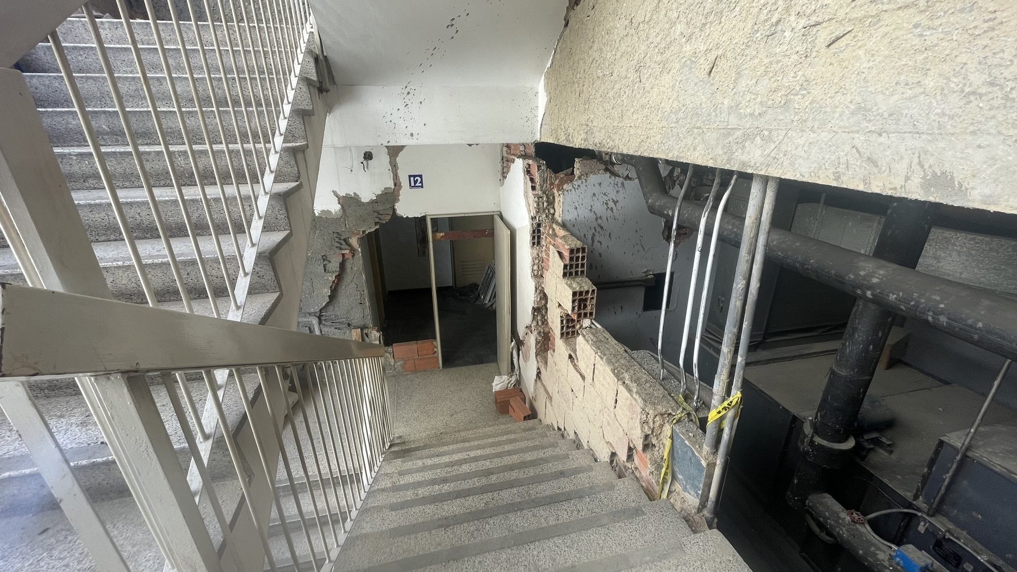 Escalera interior de una torre en Caracas con paredes abiertas y cerramientos dañados tras el sismo, en proceso de refuerzo